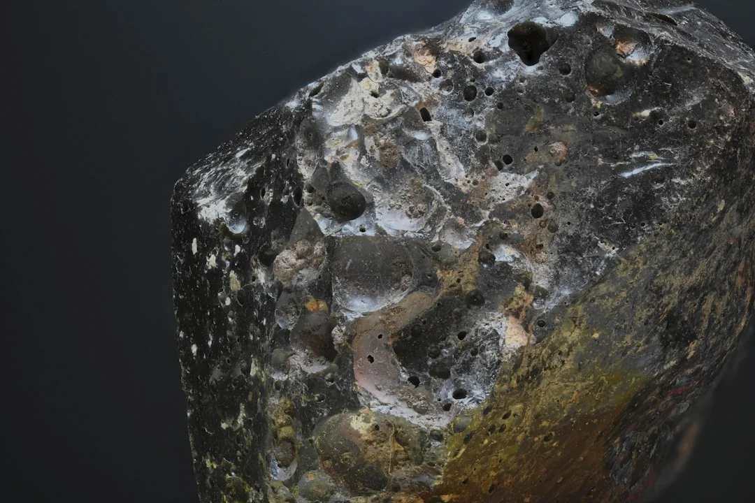 Close-up de um meteorito do tipo condrito, mostrando sua crosta de fusão escura e textura rochosa.